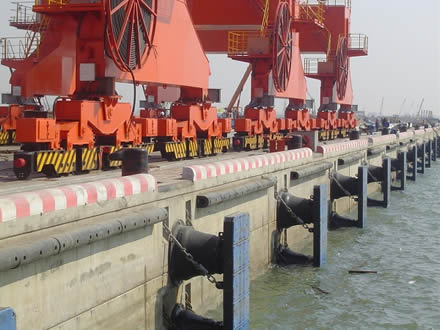 Rubber cone fenders are fixed to a dock with frontal fender panels to protect vessels during berthing.