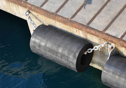 Black rubber cylindrical fender are mounted on the dock