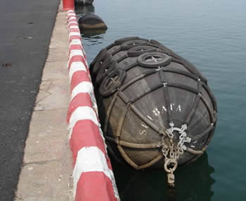 Black pneumatic rubber fenders type Ⅰ are fasten to a quay.