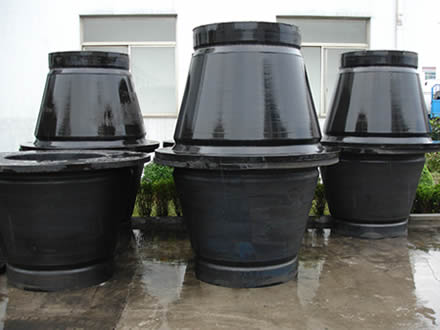 Seven black rubber cone fenders are placed in the yard of the factory