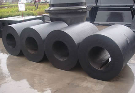 Four black rubber cylindrical fenders are placed in the factory