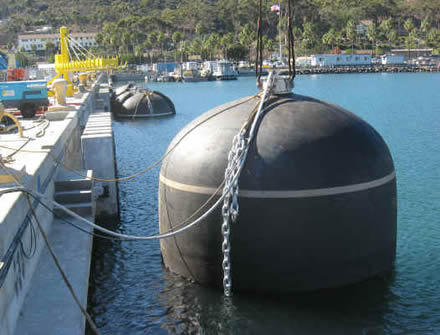 A black pneumatic rubber fender is tied to docks