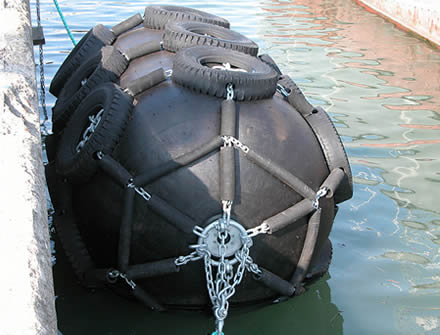 A black pneumatic rubber fender is floating on the water
